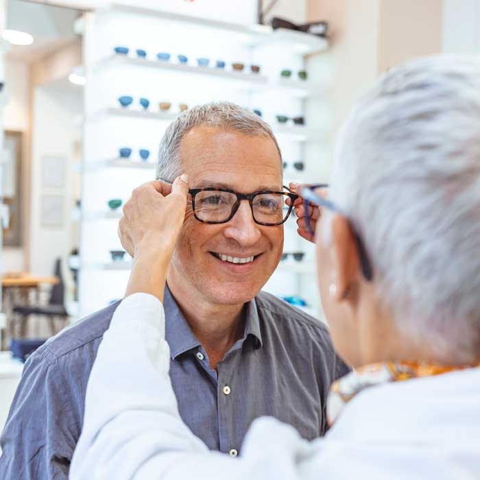 senior man being fitted for glasses at eye doctor